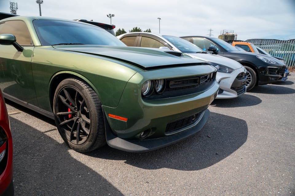 Front three-quarter view of a green Dodge Challenger parked in a row of cars.